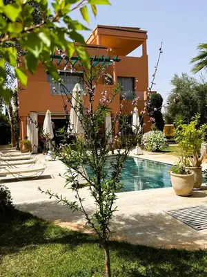 a small tree in front of a house with a pool at Villa Marrazen, lovely villa -housestaff included in Marrakech
