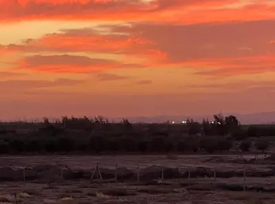 a sunset over a field with a fence at Countryside House in Marrakech