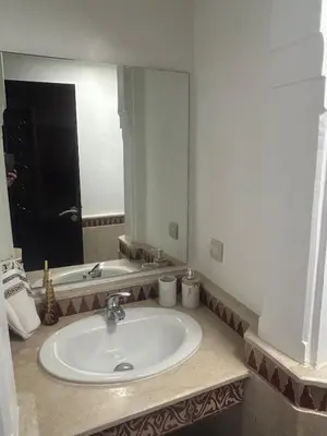 a bathroom with a sink and a large mirror at Appartement neuf hivernage in Marrakech