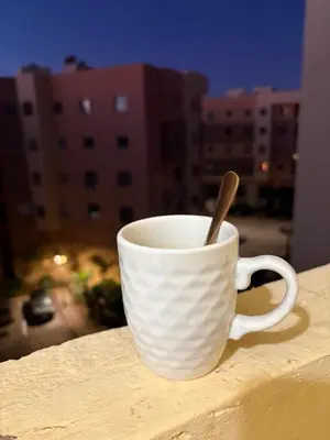 a white coffee cup with a spoon sitting on a ledge at Les jardins de Carlota in Marrakech