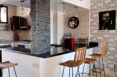 a kitchen with a black counter and two chairs at Pavillon Luxe - Jardin de l'Atlas - Golf & Waky in Sraghna