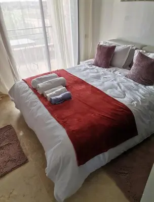 a large bed with a red and white blanket at Pavillon Luxe - Jardin de l'Atlas - Golf & Waky in Sraghna