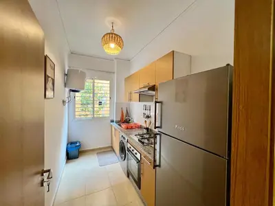 a kitchen with a refrigerator and a stove top oven at Appartement cosy et moderne familial in Marrakech