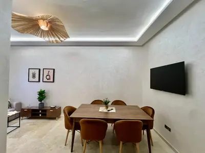 a dining room with a table and chairs and a television at Appartement cosy et moderne familial in Marrakech