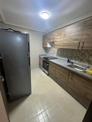 a kitchen with wooden cabinets and a stainless steel refrigerator at New and nice apartment in Marrakech