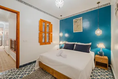 a bedroom with a large bed with a blue wall at Riad Dar Z'r in Marrakech