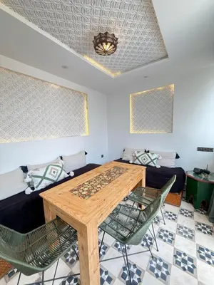 a dining room with a wooden table and chairs at Riad Marocain avec jacuzzi sur la terrasse entièrement louer avec 3 chambres pour 6 personnes dans la médina proche de la place Jemma el fna in Marrakech
