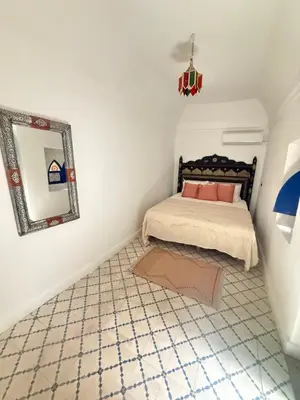a bedroom with a bed with a mirror and a tiled floor at Riad Marocain avec jacuzzi sur la terrasse entièrement louer avec 3 chambres pour 6 personnes dans la médina proche de la place Jemma el fna in Marrakech