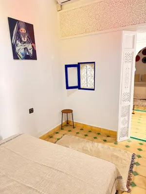 a bedroom with a bed and a painting on the wall at Riad Marocain avec jacuzzi sur la terrasse entièrement louer avec 3 chambres pour 6 personnes dans la médina proche de la place Jemma el fna in Marrakech