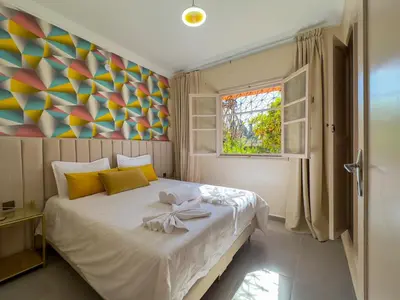 a bedroom with a large bed with a painting on the wall at Appartement lumineux avec Jardin à la palmeraie in Marrakech