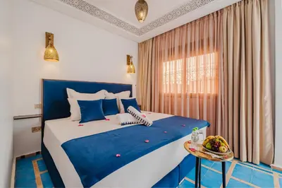 a bedroom with a blue and white bed and a window at Riad Marrakech Dar Tivawin 3 rooms With Pool Private Riad in Marrakech