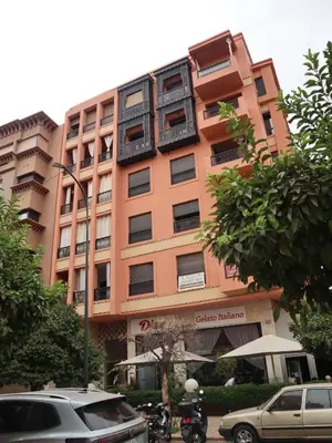 a tall orange building with cars parked in front of it at DannaMs Apartment MohamedV Hivernage in Marrakech