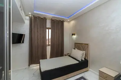 a bedroom with a bed and a tv and a window at Superbe Appart 3 pièces Moderne, Confort avec vue panoramique sur Marrakech plein centre à 7 min a pied de Gueliz in Marrakech