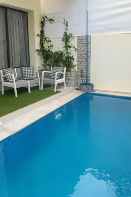 a blue swimming pool with two chairs next to a house at cozy villa 3 Rooms pool wifi -Only Family in Marrakech