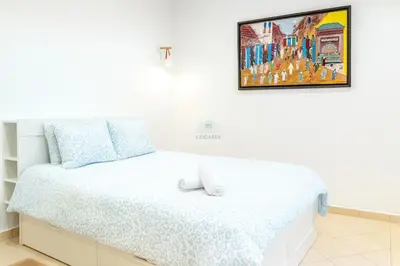 a bedroom with a white bed with a picture on the wall at Kridarek - Appartement Élégant à Marrakech in Marrakech