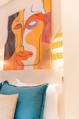 a painting of a face above a bed with a pillow at Cosy appartement avec jacuzzi in Marrakech