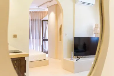 a room with a tv and a bed and a mirror at Cosy appartement avec jacuzzi in Marrakech
