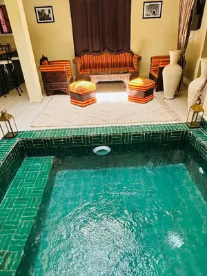 a swimming pool in a living room with a couch at Riad LALA ASMAA Riad privé in Marrakech