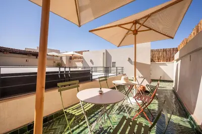a balcony with two tables and chairs and umbrellas at Riad LILIA in Marrakech
