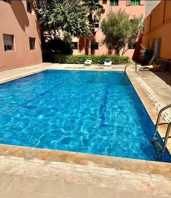 a large blue swimming pool next to a building at Stylish apartment with pool access heart of Marrakech gueliz in Marrakech