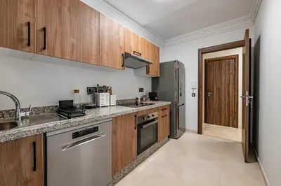 a kitchen with wooden cabinets and stainless steel appliances at Modern Apt with Balcony & Pool in Central Marrakesh in Marrakech