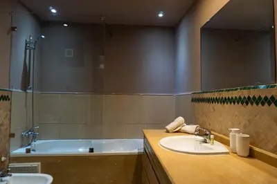 a bathroom with a sink and a tub and a mirror at Appartement HIVERNAGE deLUXE en face consulat de france et M avenu CR7 in Marrakech