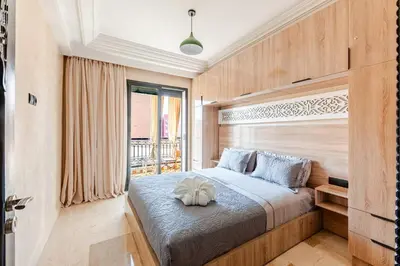 a bedroom with a bed with a wooden headboard at Calme & moderne - Piscine - Balcon - 2 SDB in Marrakech