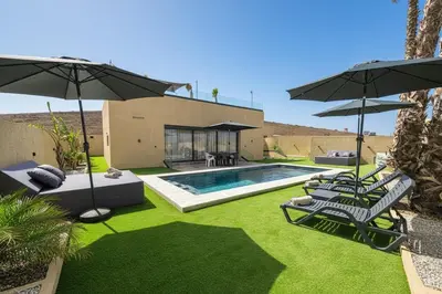a backyard with a swimming pool with chairs and umbrellas at Villa Marrakech DAR JAHYR in Douar Ouled Ahmed