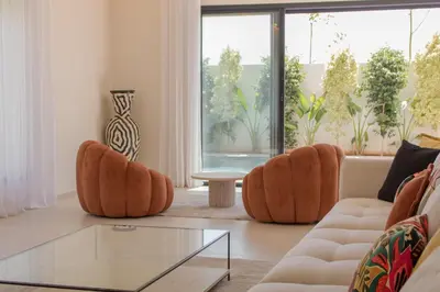 a living room with orange chairs and a glass table at Beautiful new villa with private pool in El Rhechat