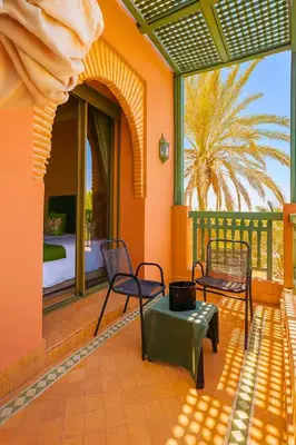 a patio with chairs and a bed in the background at L'Oasis Chic Palmeraie Marrakech Piscine & Petit Déj Offert in Marrakech