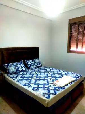 a bedroom with a bed with a blue and white quilt at 2-bedroom apartment in Marrakech