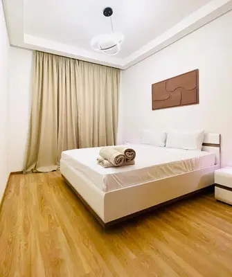 a bedroom with a large white bed with wooden floors at Cozy appartement à noria golf in Marrakech