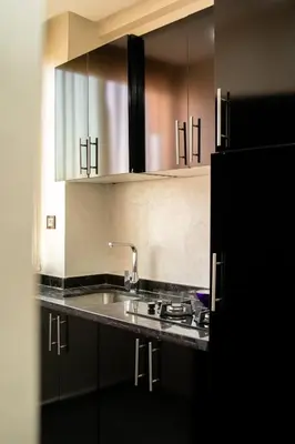a kitchen with black cabinets and a sink at Cozy apartment in the hypercenter in Marrakech