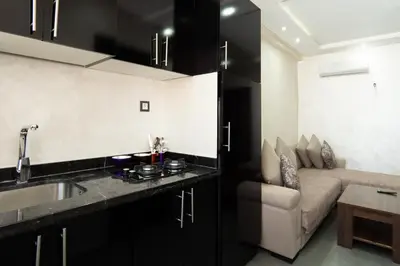a kitchen with black cabinets and a couch in a room at Cozy apartment in the hypercenter in Marrakech