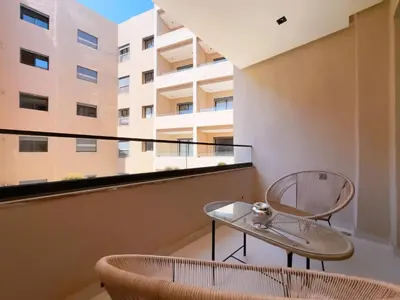 a balcony with two chairs and a table in front of a building at Menara Garden Wifi Parking Piscine in Marrakech