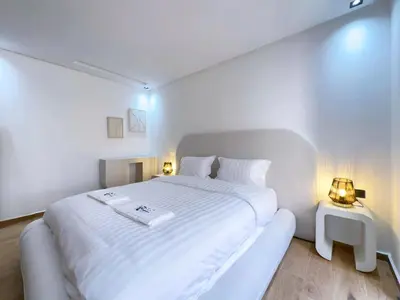 a white bedroom with a large white bed with two lamps at Menara Garden Wifi Parking Piscine in Marrakech