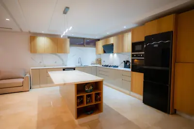 a kitchen with a black refrigerator and wooden cabinets at Villa Akenza - Cinema - Swiming pool in Marrakech