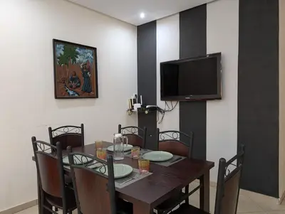a dining room with a table and a flat screen tv at Le Cocon Nature in Marrakech