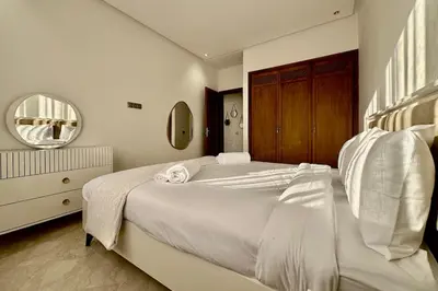 a white bedroom with a large bed and a mirror at Top floor apartment in Gueliz with Balcony in Marrakech