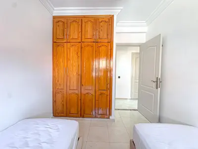 a bedroom with two beds and a wooden door at Lumière d'Atlas Calme et Confort in Marrakech