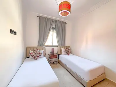 two beds in a room with a window at Lumière d'Atlas Calme et Confort in Marrakech