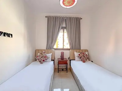 two beds in a room with a window at Lumière d'Atlas Calme et Confort in Marrakech