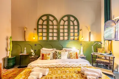 a bedroom with a large bed with a green headboard at DAR MA ITTO Charming luxurious Medina Cocoon in Marrakech