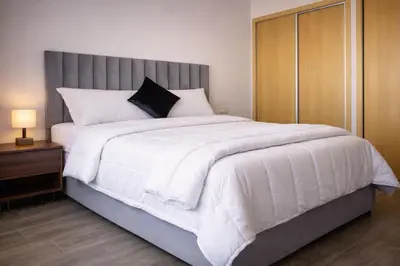 a bedroom with a large white bed with a gray headboard at 2 bedrooms appartement les palmiers de targa in Marrakech