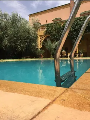 a swimming pool with blue water in front of a building at Villa Louise in Marrakech