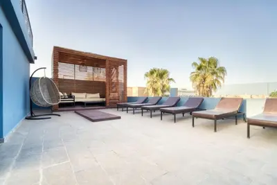 a group of chairs on a patio with palm trees at Design Art Gallery Apartment Marrakech swimming pool on the Roof in Marrakech