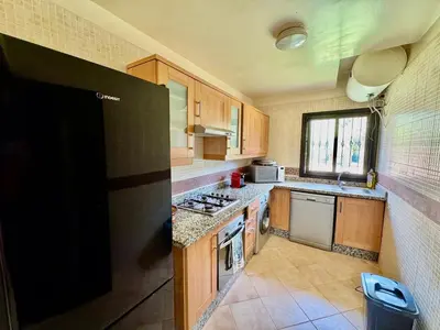 a kitchen with wooden cabinets and a black refrigerator at Private Garden Villa - Rooftop, BBQ, Pools and Views in Marrakech