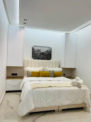 a white bedroom with a large bed with yellow pillows at L'aube de l'éveinage 2 bedrooms Marrakech station in Marrakech