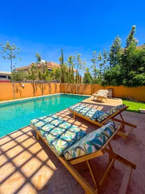 a swimming pool with two beds next to a swimming pool at Sublime Villa avec Piscine et Jardin à Marrakech in El Rhechat