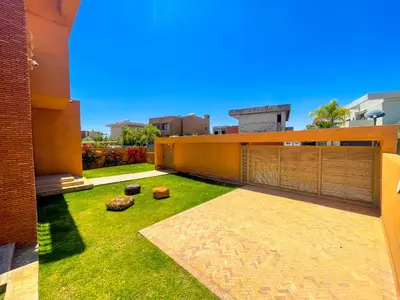 a backyard of a building with grass and a fence at Sublime Villa avec Piscine et Jardin à Marrakech in El Rhechat